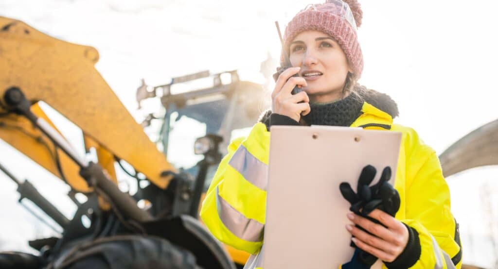 Woman with walkie talky on compost plant and wheel loader